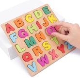 Colorful wooden alphabet puzzle with a hand interacting with it on a white background