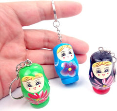 Three colorful keychains shaped like Russian nesting dolls held by a hand.