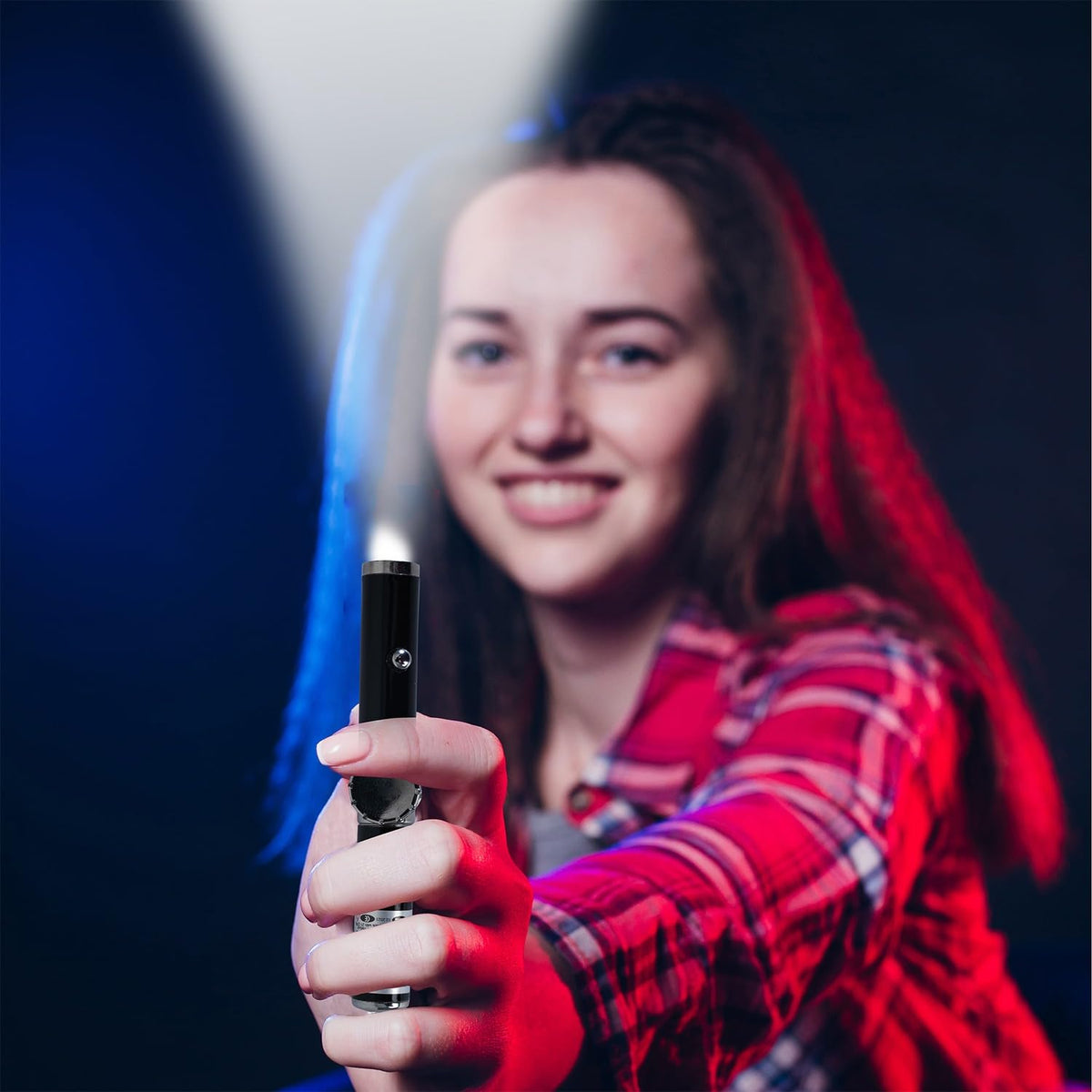 Person holding a light-up toy sword with a dark background