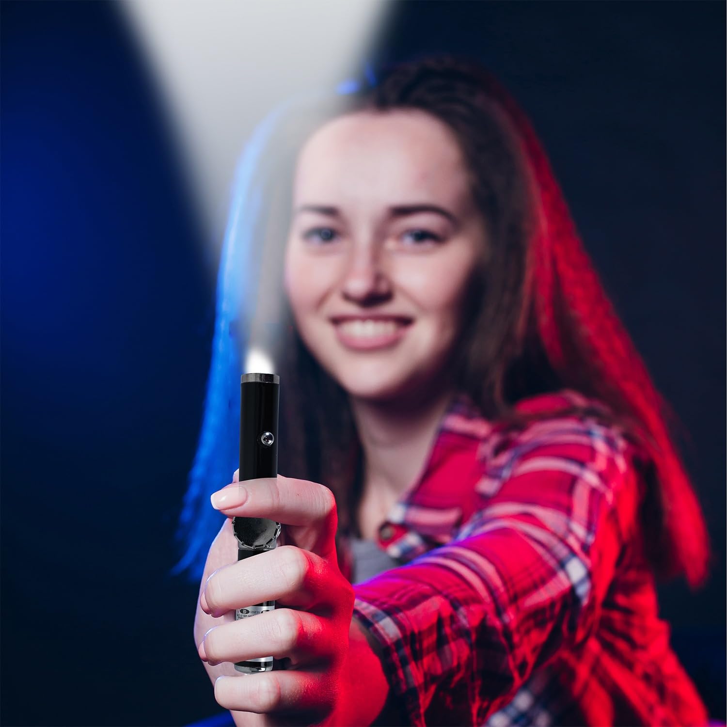 Person holding a light-up toy sword with a dark background