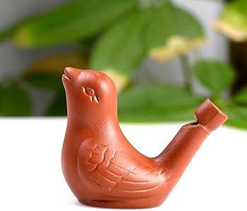 Red clay bird-shaped object on a white surface with green leaves in the background