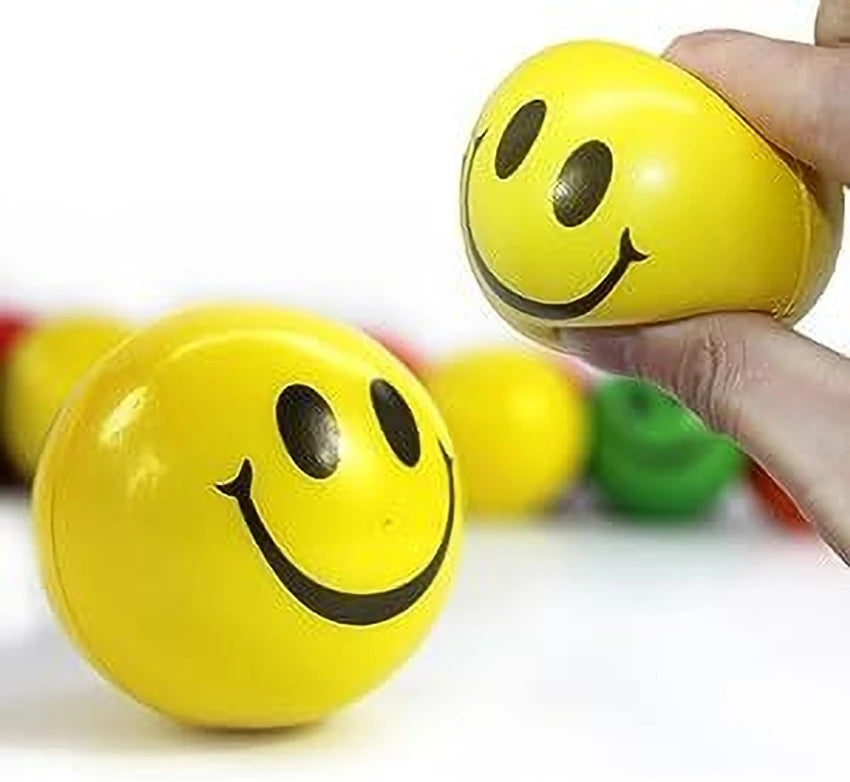 Yellow smiley face stress balls with a hand squeezing one, on a white background.