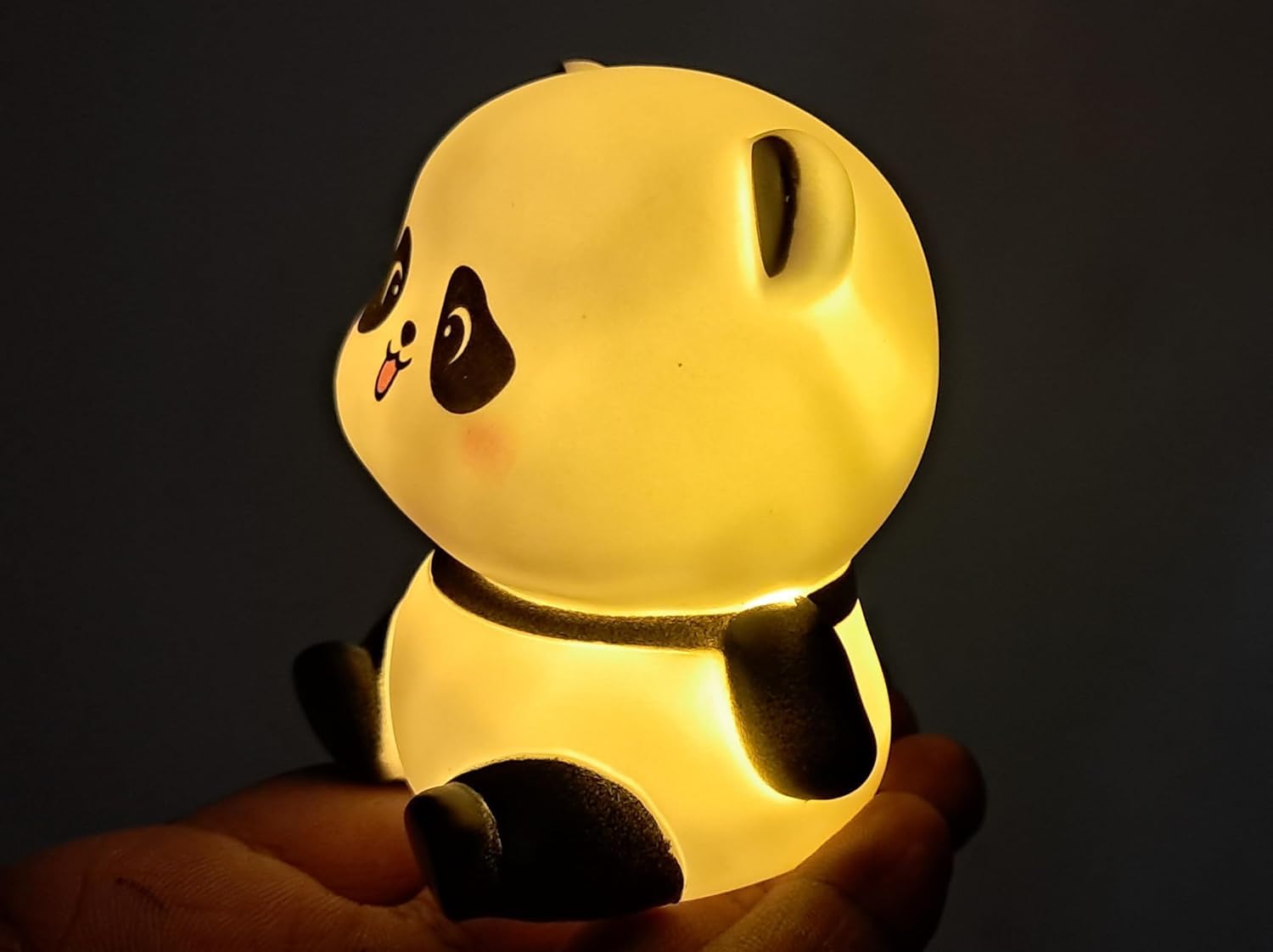 Cute panda-shaped night light held in a hand against a dark background
