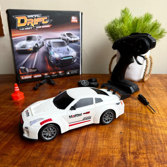 Toy drift car with remote control on a wooden surface, next to a book titled 'Racing Drift'.
